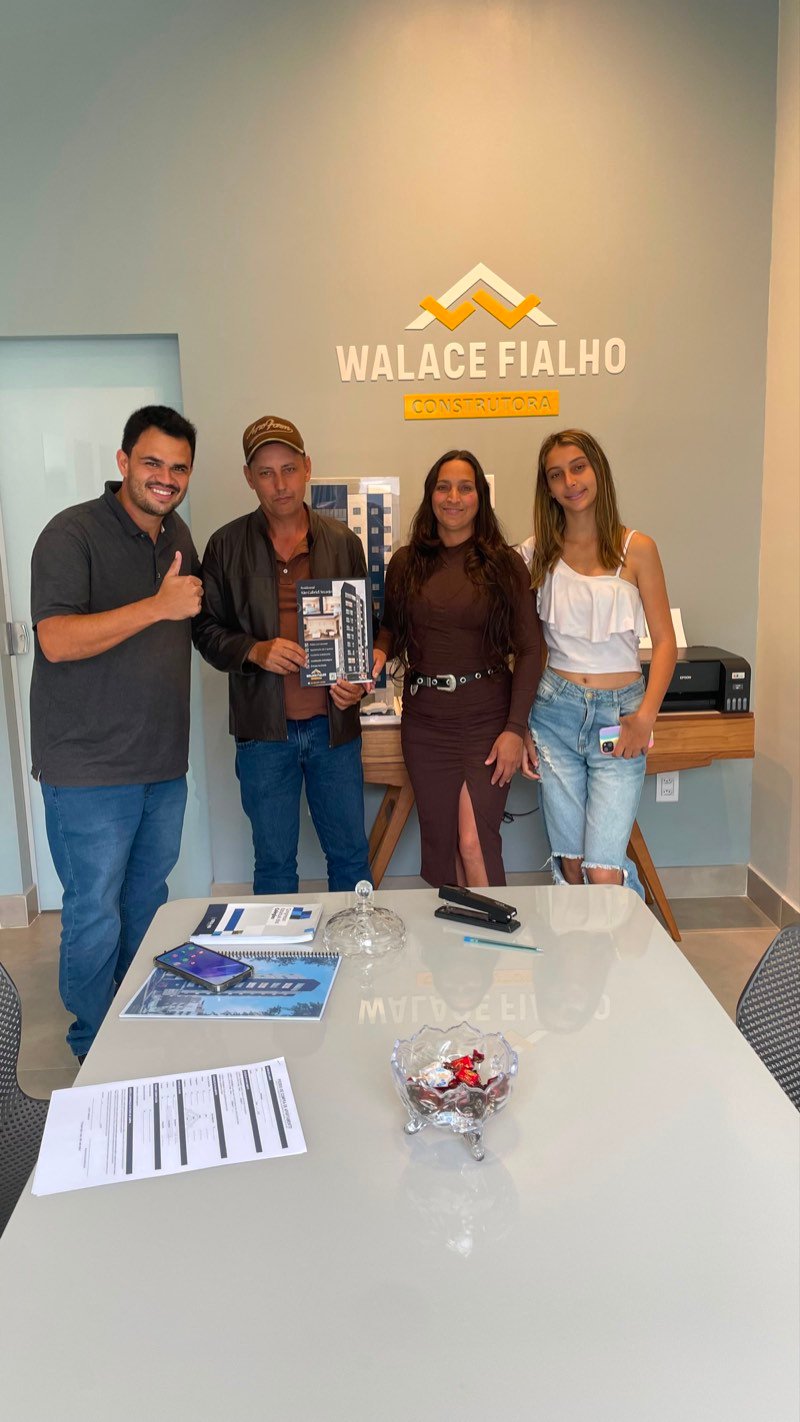 Vendedora e compradores reunidos na mesa do stand de vendas, fechando negócio.